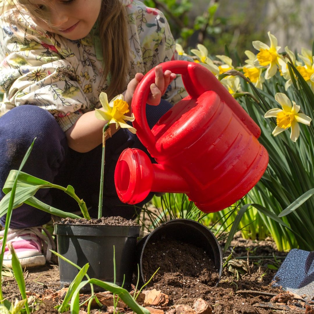 Little girl planting flowers in the garden, Earth Day. Kid helping at the farm.